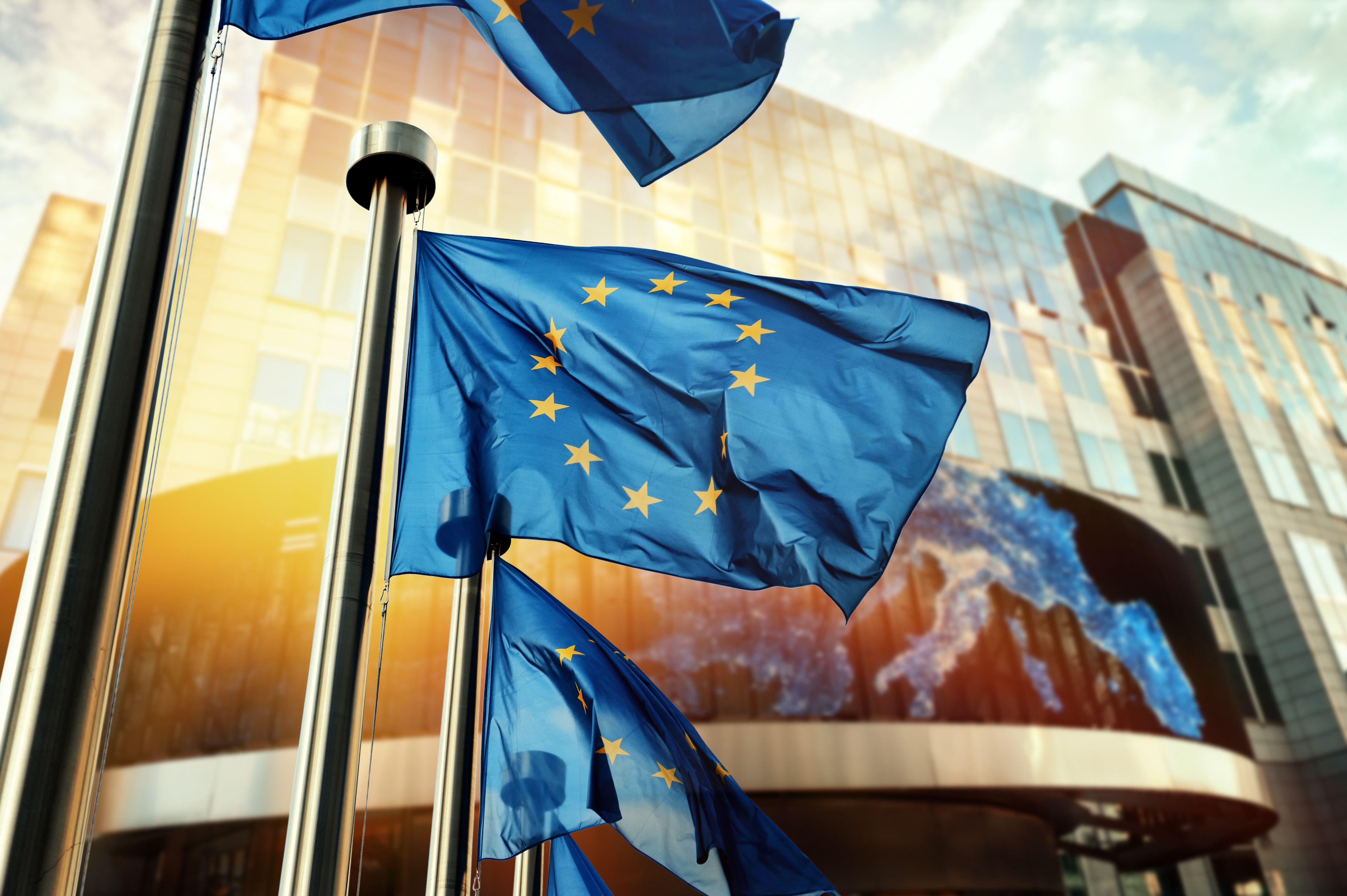 EU flags billowing in front of glass building