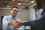 Man laughing and shaking hands with another person in an office