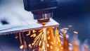 A drill bit bearing down on a steel plate, creating sparks