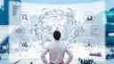 Man in business attire looking at large, futuristic data screen, with graphs and charts shown and a network of trade routes