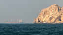 Red-rock cliff face with oil tanker in background