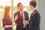 A woman and two men in a meeting, wearing business attire, with the two men shaking hands
