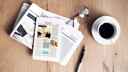 Newspapers laid on a wooden with fresh coffee mug and pen