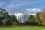 The front lawn of the White House, in Washington DC, with an Americna flag flying against a blue and cloudy sky