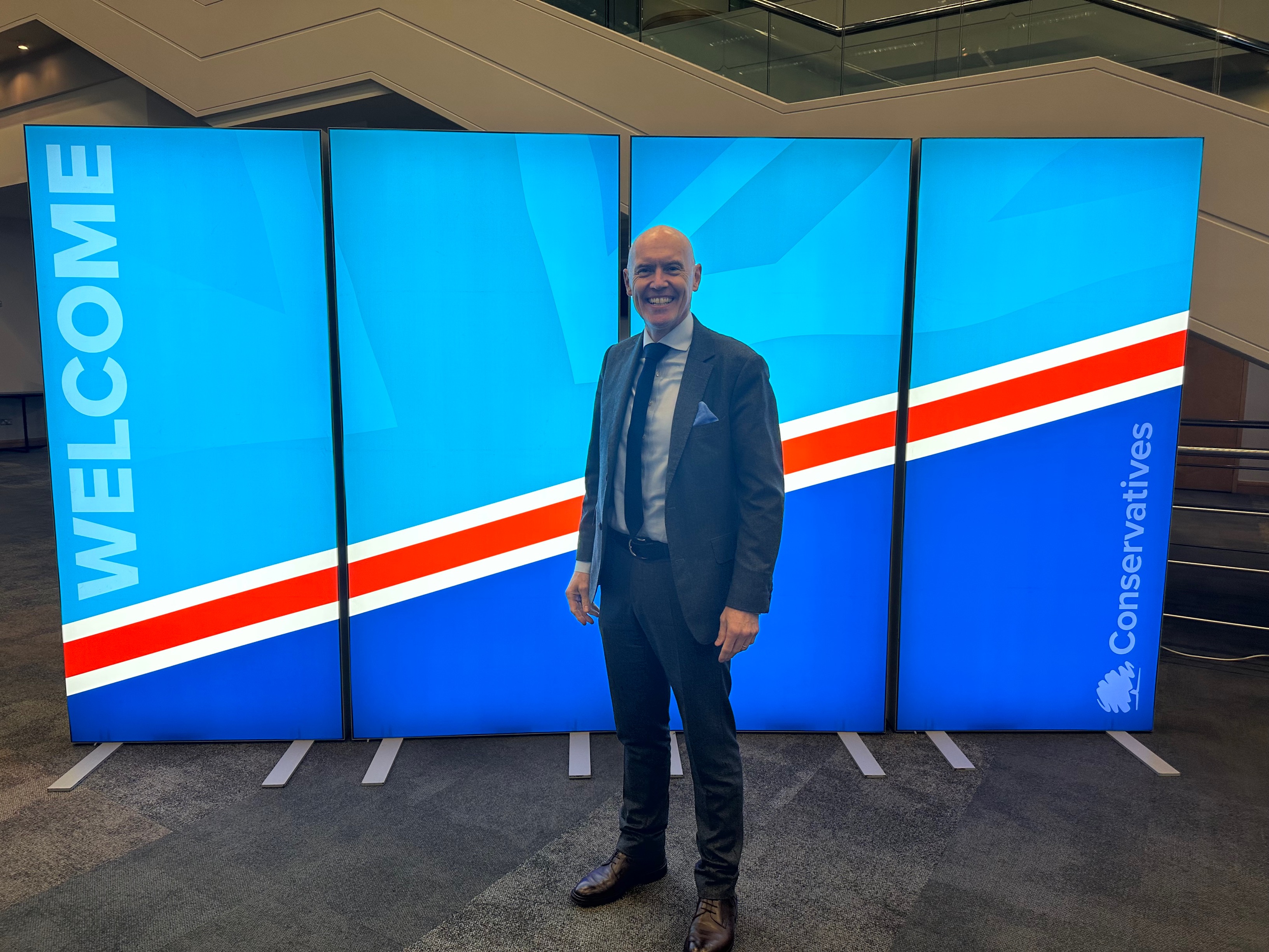 Marco Forgione in front of Conservative business day banner